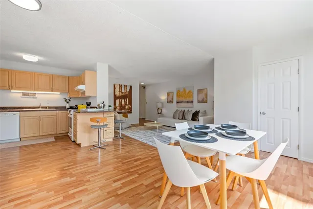 a kitchen with stainless steel appliances kitchen island granite countertop a dining table chairs and a refrigerator