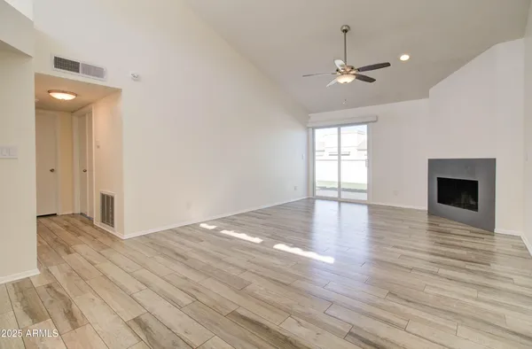 a view of empty room with wooden floor and fan