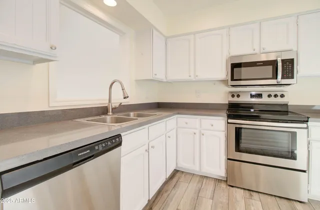 a kitchen with stainless steel appliances white cabinets a stove a microwave and a refrigerator