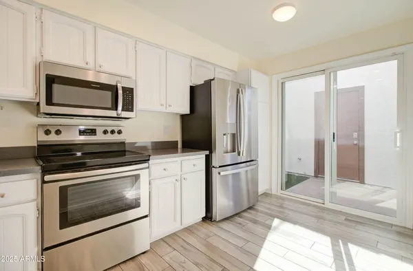 a kitchen with stainless steel appliances granite countertop a stove top oven a sink dishwasher and white cabinets with wooden floor