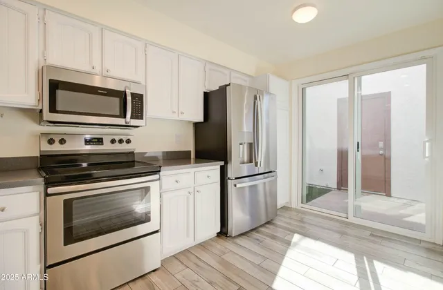 a kitchen with stainless steel appliances granite countertop a stove top oven a sink dishwasher and white cabinets with wooden floor