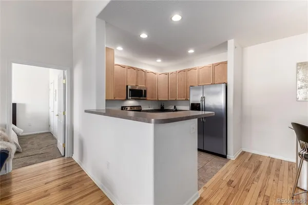 a kitchen with stainless steel appliances granite countertop a refrigerator a sink and a stove with wooden floors