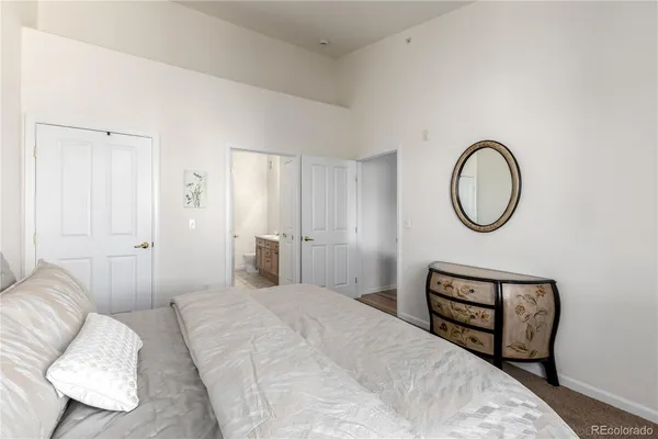 a bedroom with a bed a mirror and a potted plant