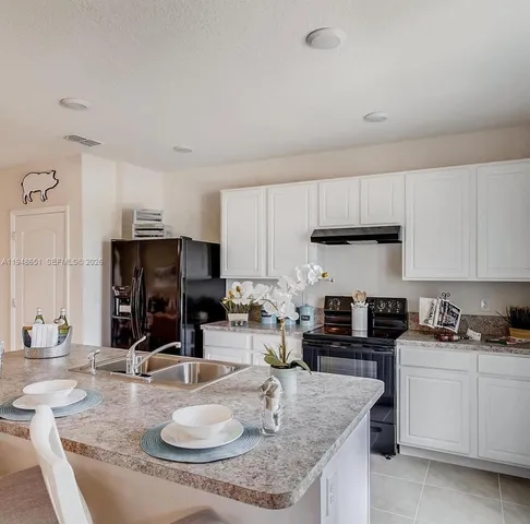 a kitchen with kitchen island granite countertop a sink a stove and cabinets