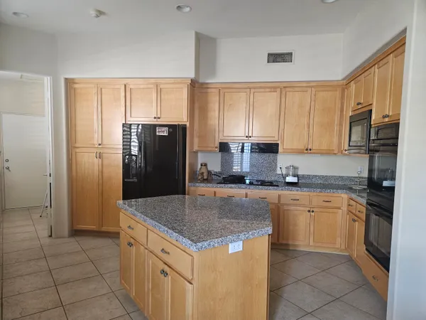 a kitchen with stainless steel appliances granite countertop a refrigerator a stove a sink a microwave and island