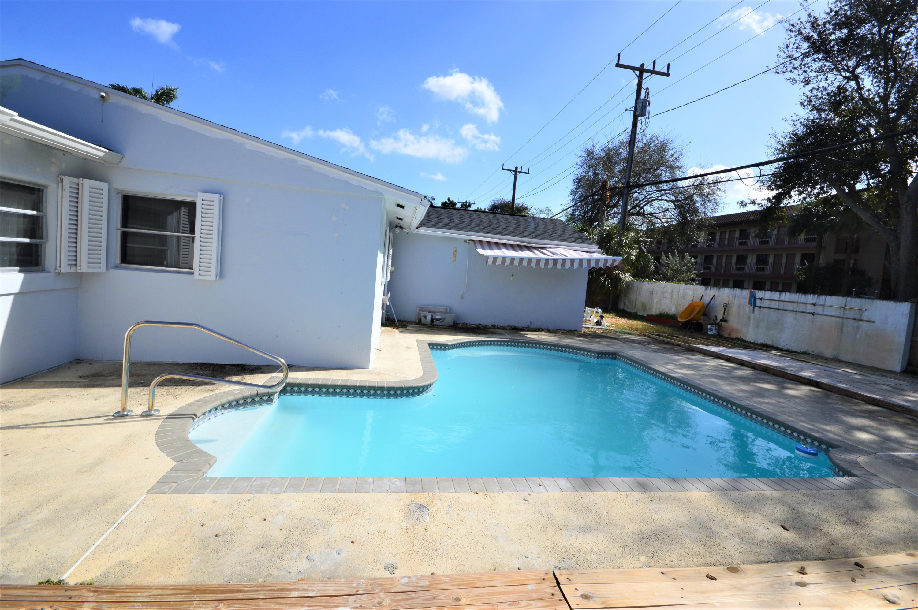 4092 Rochester Street Palm Beach Gardens, FL 33410 - Photo 6 of 28 a swimming pool with a yard and palm trees