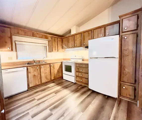 a kitchen with a refrigerator a stove and white cabinets with wooden floor
