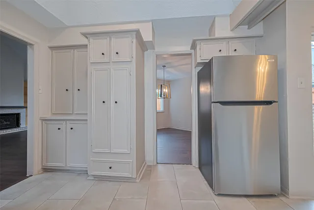 a view of a refrigerator in kitchen and white cabinets
