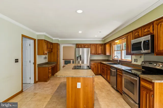 a large kitchen with stainless steel appliances granite countertop a large counter top a stove and a refrigerator