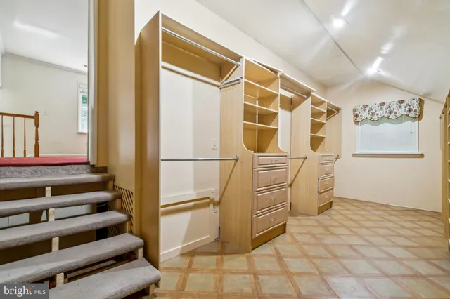 a view of walk in closet with clothes and white walls