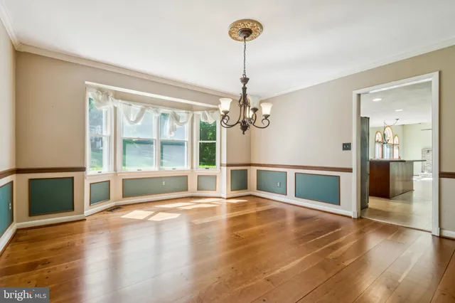 a view of an empty room with wooden floor and a kitchen
