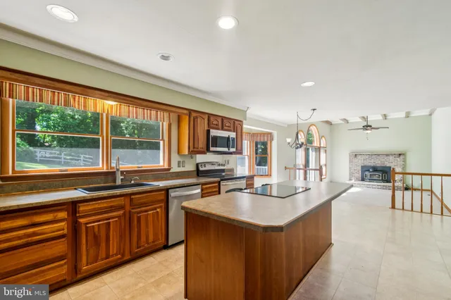 a kitchen with counter top space sink stove and living room view