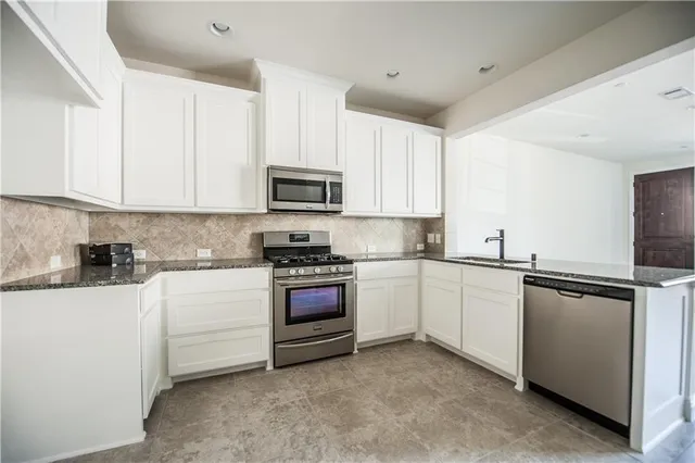 a kitchen with stainless steel appliances granite countertop a sink and white cabinets