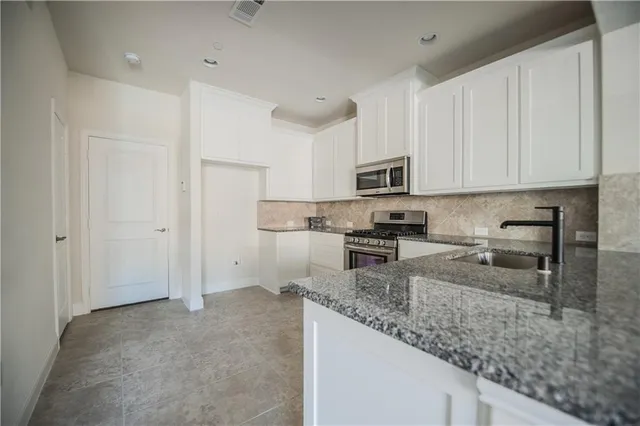 a kitchen with stainless steel appliances granite countertop a sink refrigerator and cabinets