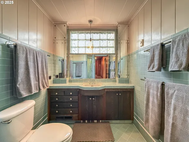 a bathroom with a granite countertop toilet sink and mirror