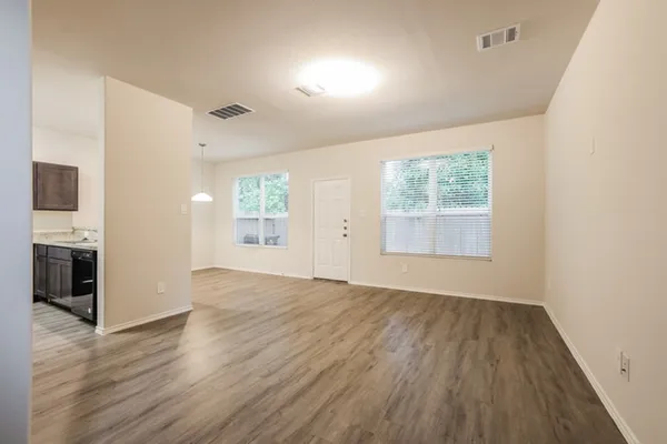 an empty room with wooden floor fireplace and windows
