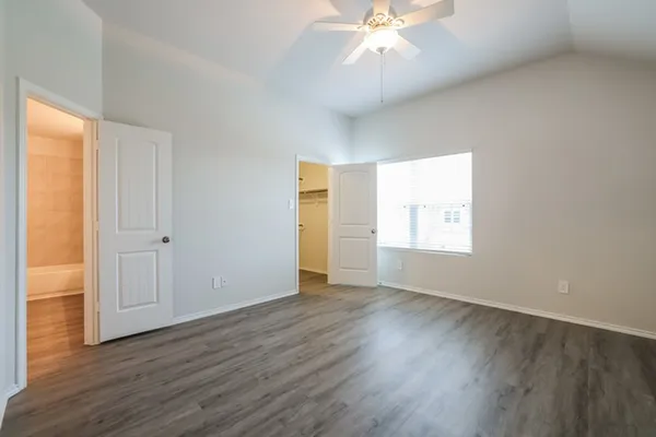 an empty room with wooden floor chandelier fan and windows