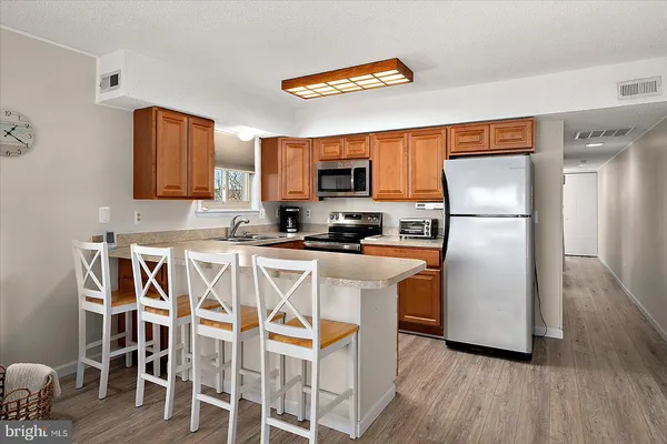 a kitchen with stainless steel appliances granite countertop a refrigerator a stove a sink and a dining table with wooden floor