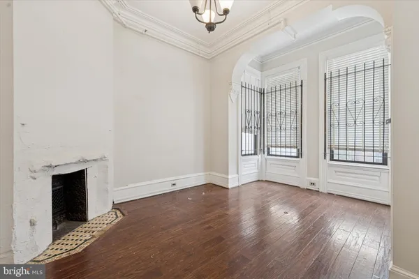 an empty room with wooden floor fireplace and windows