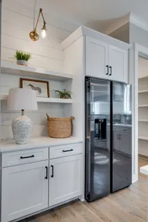 a kitchen with white cabinets and refrigerator