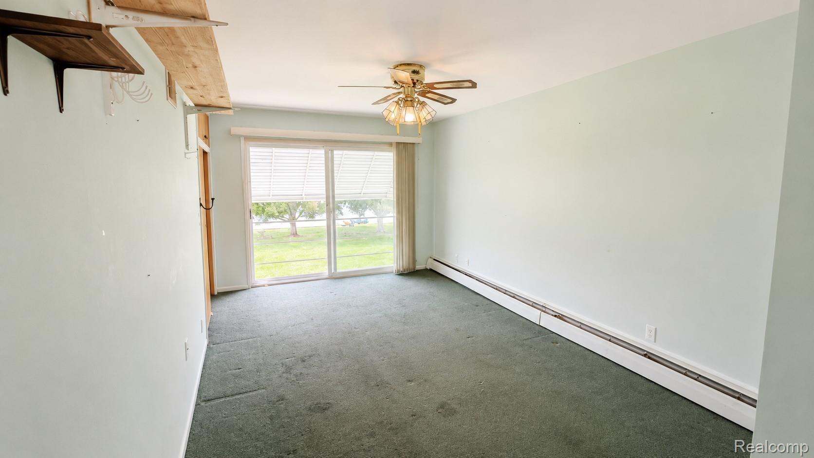 26945 Milford Road, Unit 34 New Hudson, MI 48165 - Photo 14 of 16 Spacious room featuring light blue walls, green carpeting, and a ceiling fan with integrated lighting