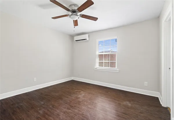 an empty room with wooden floor ceiling fan and windows