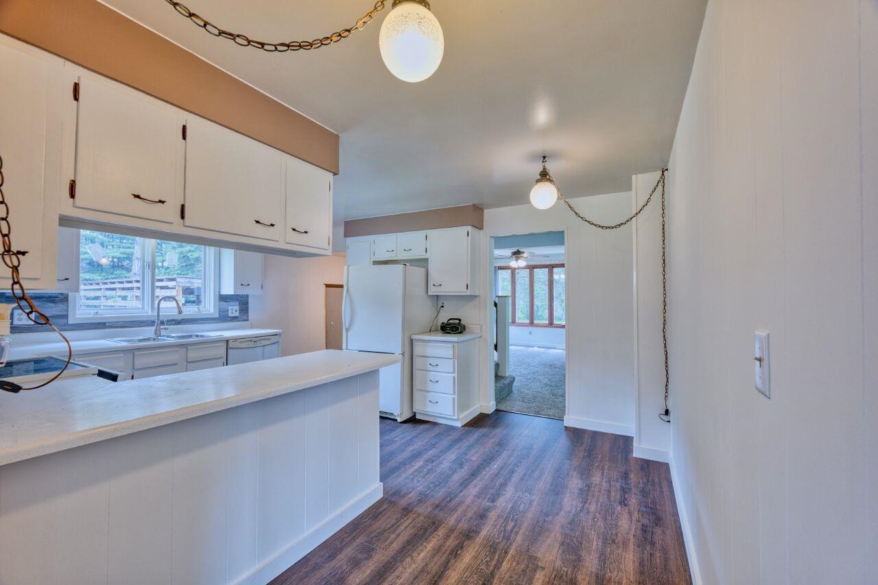 4755 Judd Road Gilbert, MN 55741 - Photo 11 of 50 Kitchen with a sink, white appliances, light countertops, white cabinets, and dark wood-type flooring