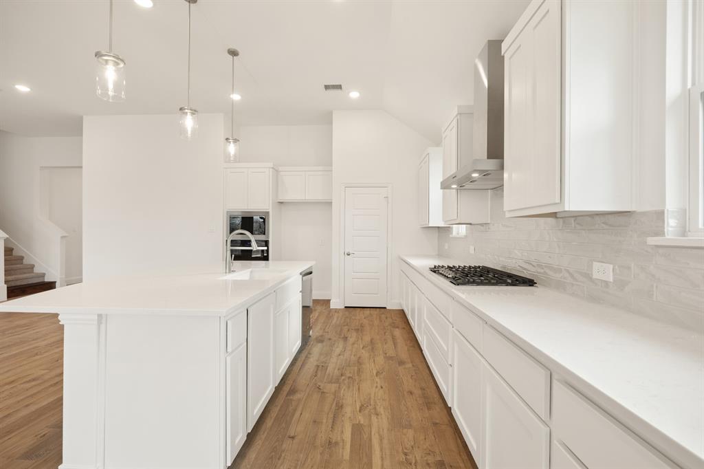 735 Oak Lavon, TX 75166 - Photo 33 of 39 a kitchen with kitchen island a stove a sink a refrigerator and white cabinets with wooden floor