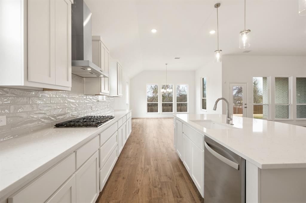 735 Oak Lavon, TX 75166 - Photo 34 of 39 a large kitchen with granite countertop a large stove a sink dishwasher and white cabinets with wooden floor