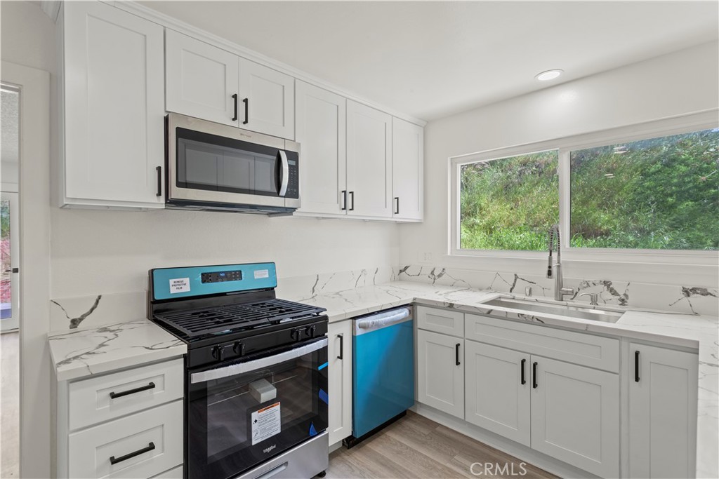 a kitchen with stainless steel appliances white cabinets granite counter tops and a sink