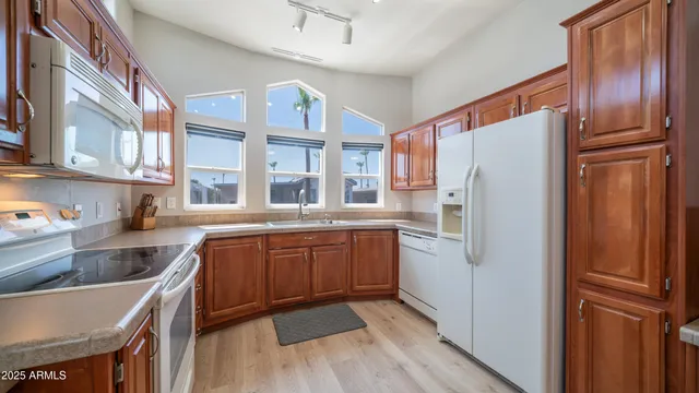 a kitchen with stainless steel appliances granite countertop a refrigerator a stove and a sink with wooden floor