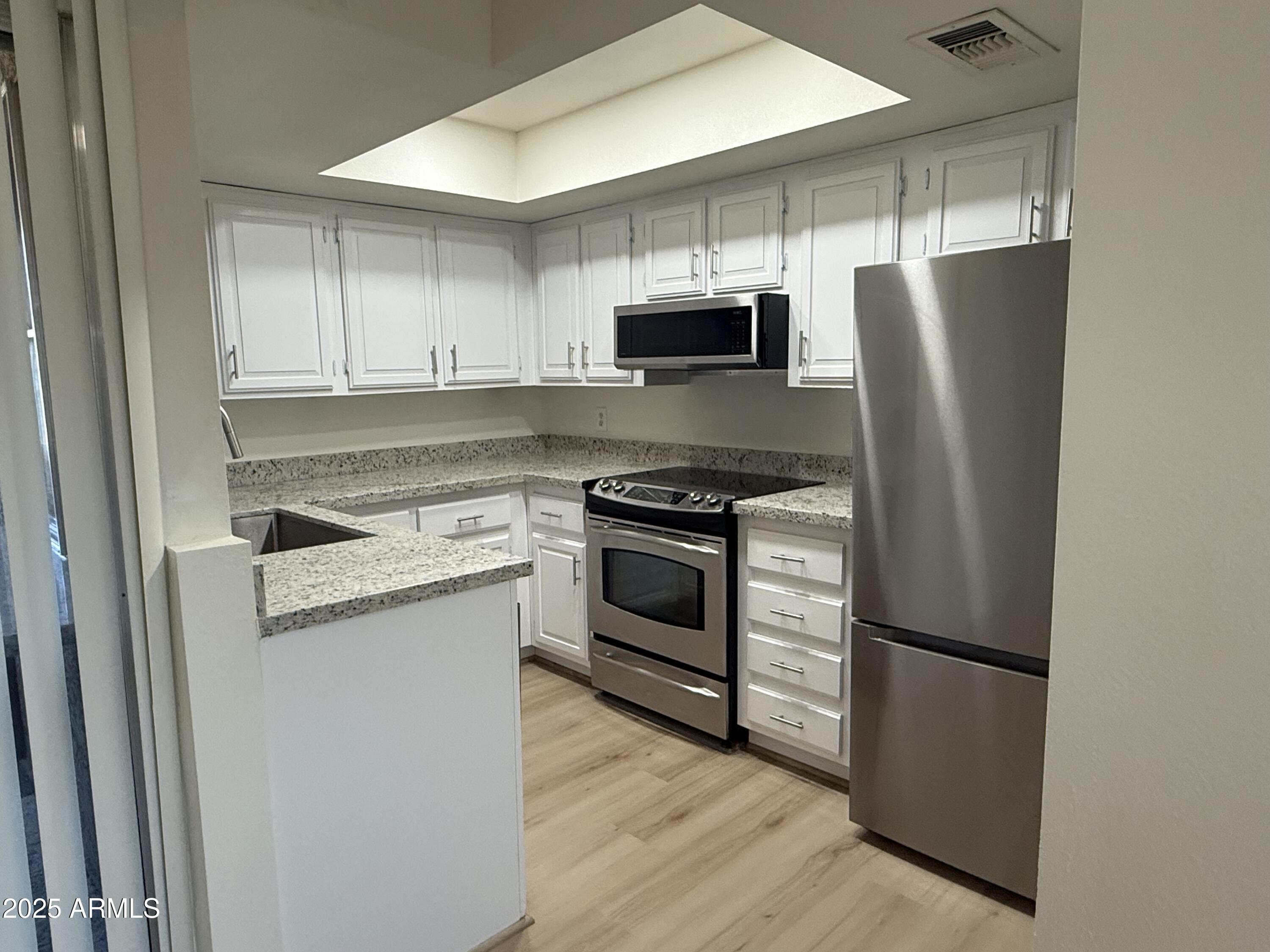 461 West Holmes Avenue, Unit 342 Mesa, AZ 85210 - Photo 12 of 21 a kitchen with stainless steel appliances white cabinets and wooden floor