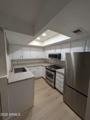 a kitchen with stainless steel appliances granite countertop a refrigerator a stove and a sink with wooden floor