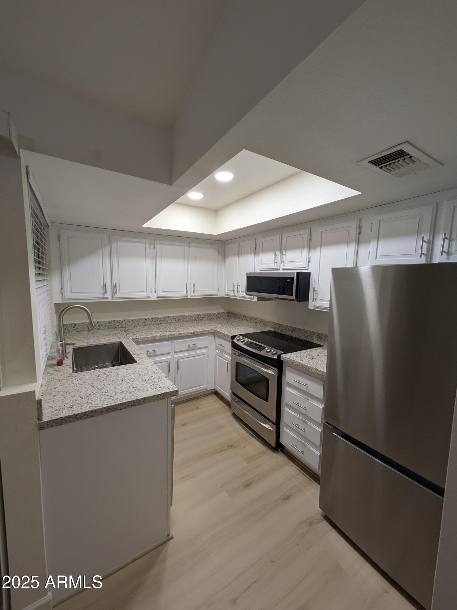 461 West Holmes Avenue, Unit 342 Mesa, AZ 85210 - Photo 13 of 21 a kitchen with stainless steel appliances granite countertop a refrigerator a stove and a sink with wooden floor