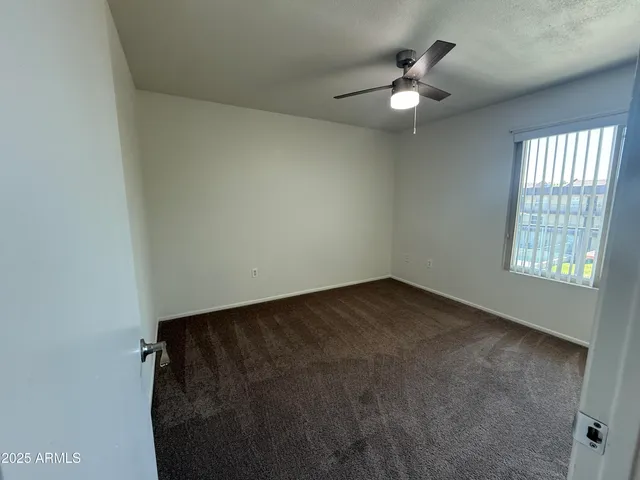 an empty room with a window and a ceiling fan