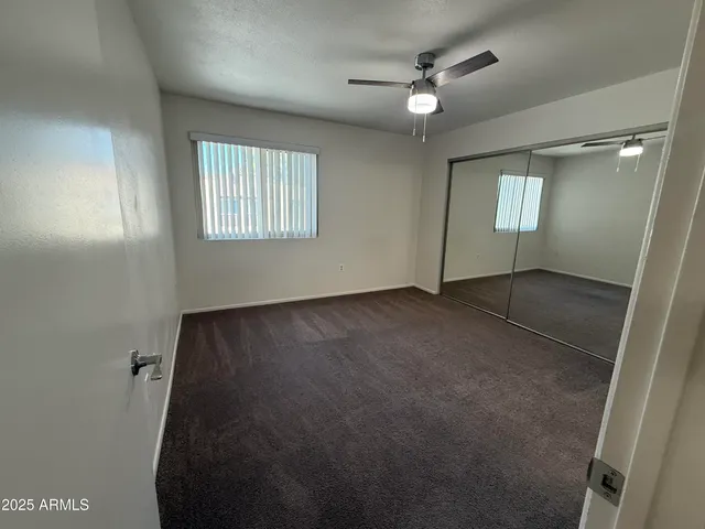 an empty room with windows and fan
