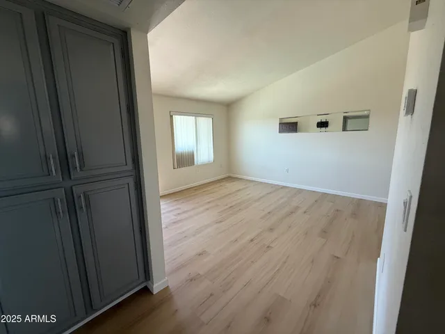 an empty room with wooden floor closet and windows