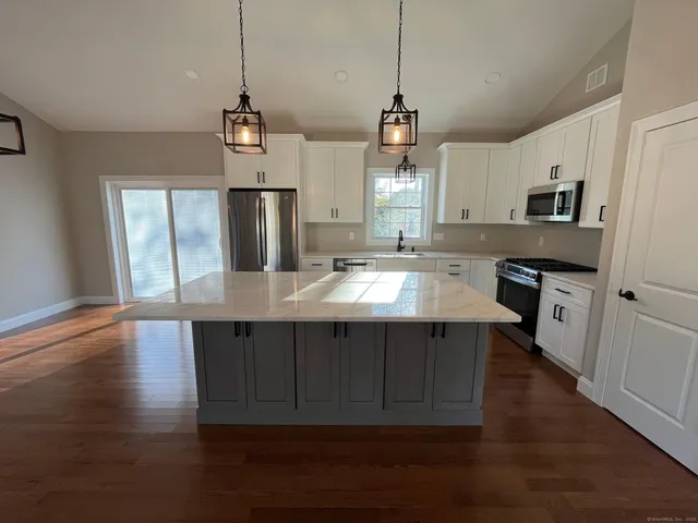 a kitchen with a sink chandelier and wooden floor