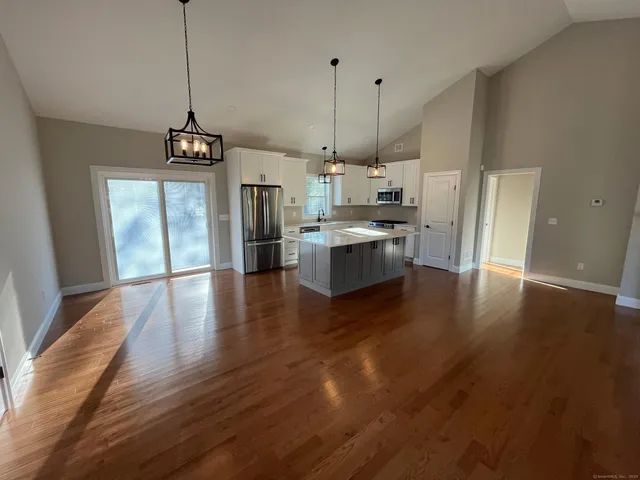 a open kitchen with stainless steel appliances granite countertop a stove and a wooden floors