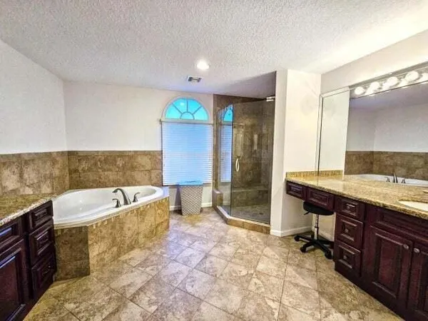 a spacious bathroom with a tub sink and mirror