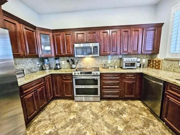 a kitchen with stainless steel appliances granite countertop a stove top oven a sink and dishwasher a oven with wooden cabinets