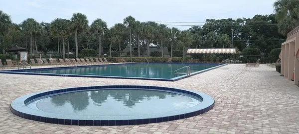 a view of a swimming pool with a yard and trees in the background