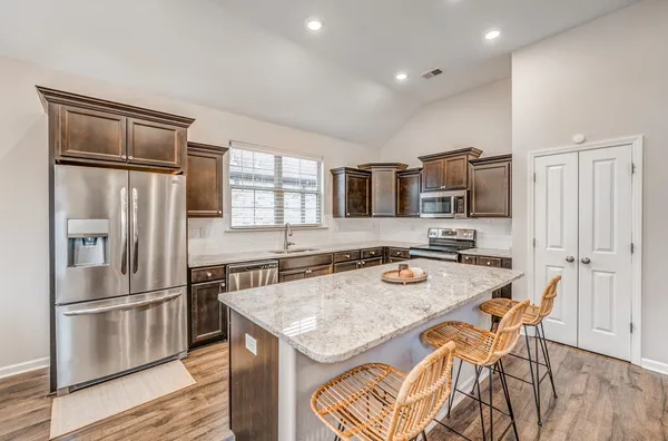 a kitchen with stainless steel appliances granite countertop a sink a stove a refrigerator and island