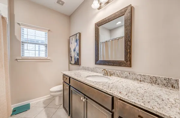 a bathroom with a granite countertop sink a toilet and a mirror