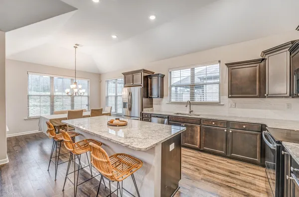a kitchen with stainless steel appliances granite countertop wooden floor and large windows