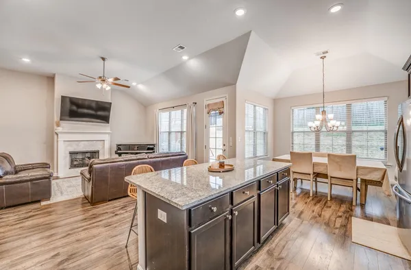 a large kitchen with kitchen island a stove a sink a dining table and chairs with wooden floor