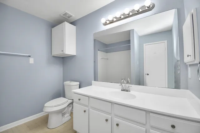a view of an empty room with wooden floor and a ceiling fan