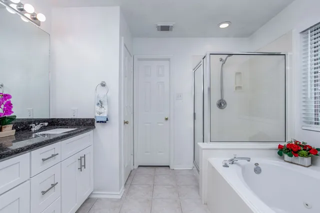 a bathroom with a granite countertop sink a mirror and a bathtub