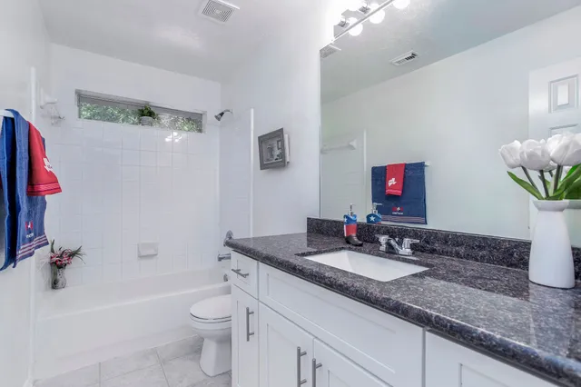 a bathroom with a granite countertop sink a toilet and shower