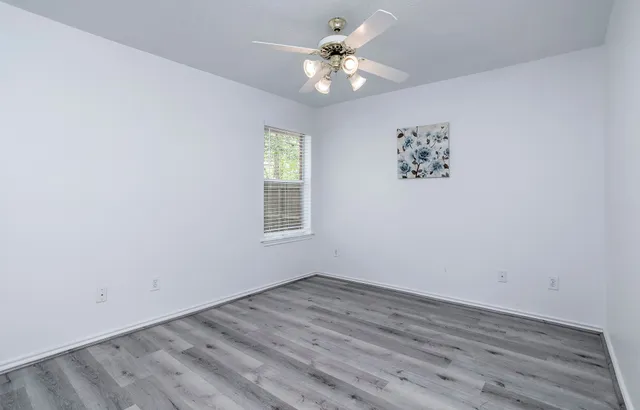 an empty room with a window and a fan